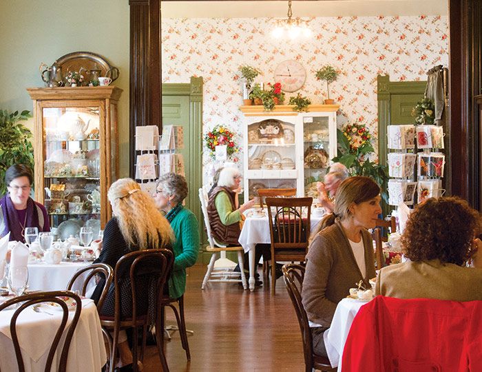 people sitting at tables in a restaurant with white tablecloths and red napkins