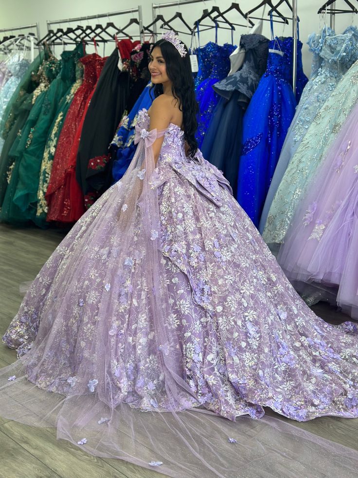 a woman in a purple dress standing next to dresses on display at a bridal event