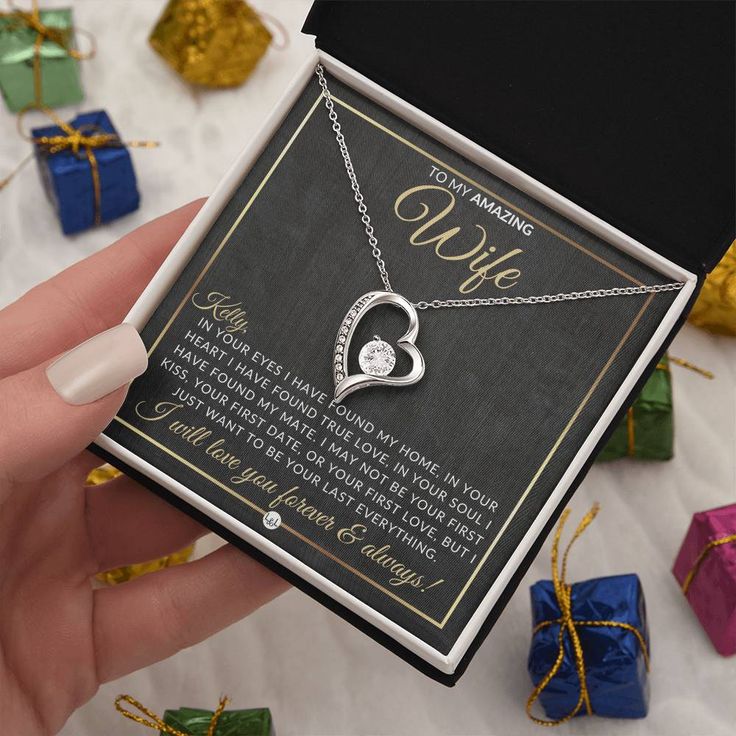 a person holding a necklace with a heart on it in front of gift boxes and presents