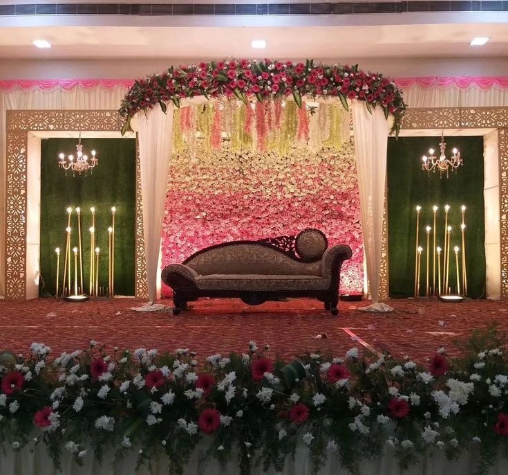 a couch sitting in front of a stage decorated with flowers and candles for a wedding