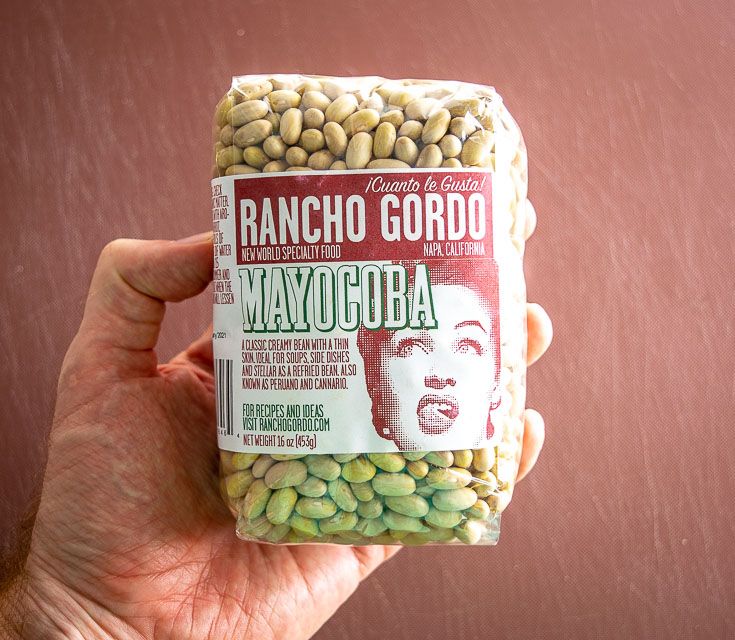 a hand holding up a bag of beans with a woman's face on it