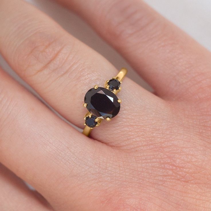 With a brilliant cut like that, this ring is nothing but pure brilliance in itself. For lovers of darker colors, the Khloe ring with Black Spinel with two side black spinels is a perfect choice. Celebrate your milestones or special occasions with this ring as the perfect gift for a friend, as an anniversary ring, or just as an everyday celebration of life in general. Details: Center stone Gemstone: Black Spinel Stone Shape: Oval Measurements: approx. 9x7mm Side stones Gemstone: Black Spinel Shap Black Oval Sapphire Promise Ring, Classic Black Oval Sapphire Ring, Classic Black Sapphire Oval Ring, Elegant Oval Black Spinel Rings, Classic Black Spinel Sapphire Ring For Anniversary, Black Heirloom Ring With Center Stone, Heirloom Black Ring With Center Stone, Black Oval Sapphire Ring With Center Stone, Black Sapphire Ring With Oval Center Stone