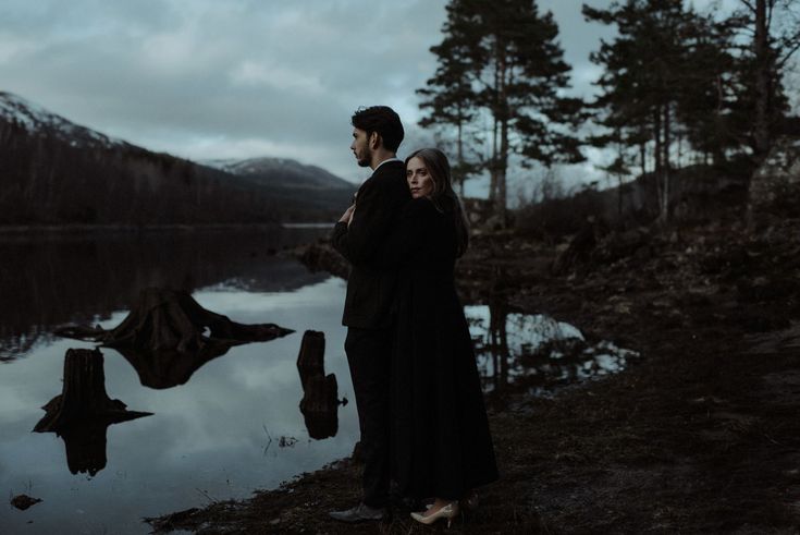 a man and woman standing next to each other near water