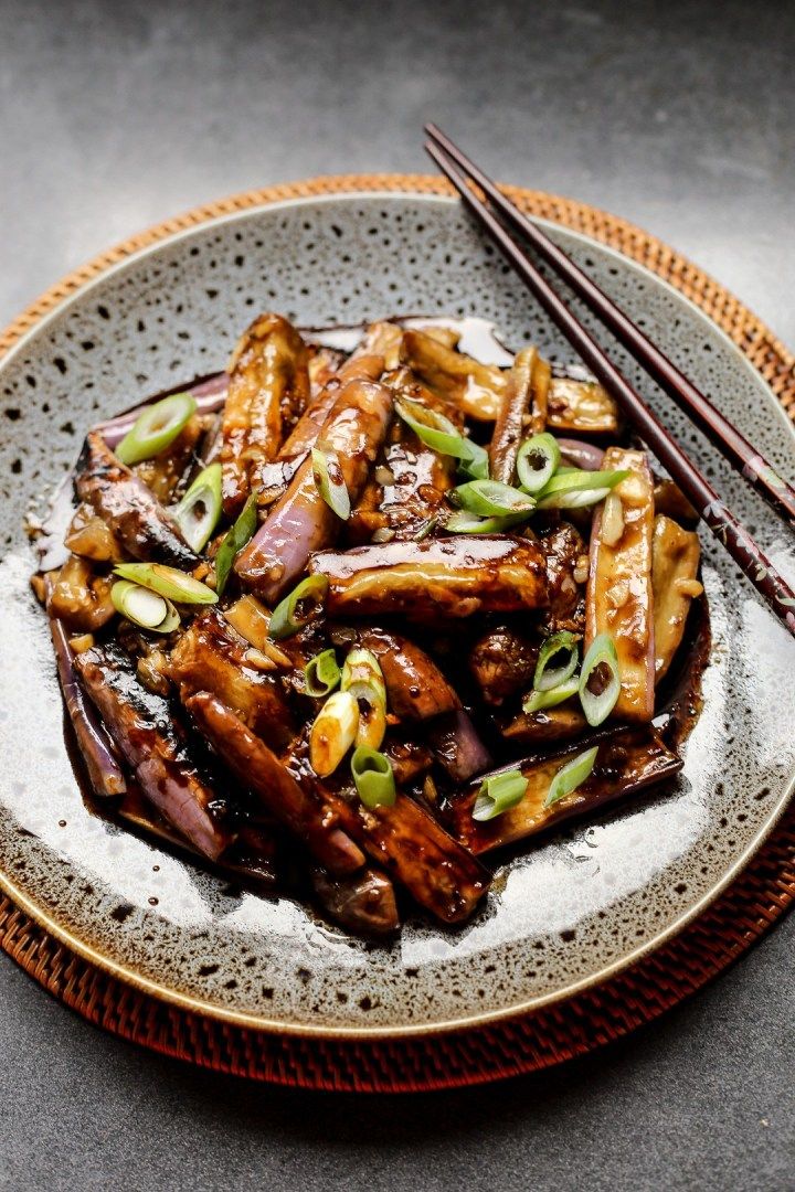 a plate topped with meat and vegetables next to chopsticks