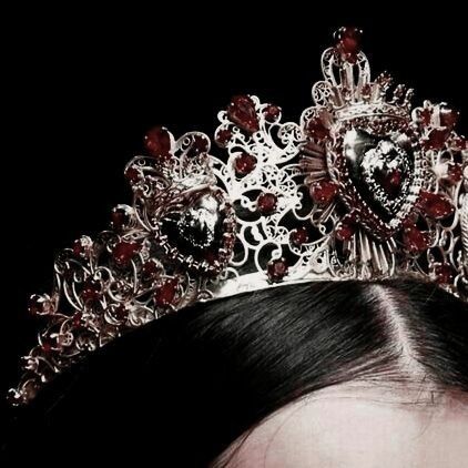 a close up of a woman wearing a tiara with red stones on her head