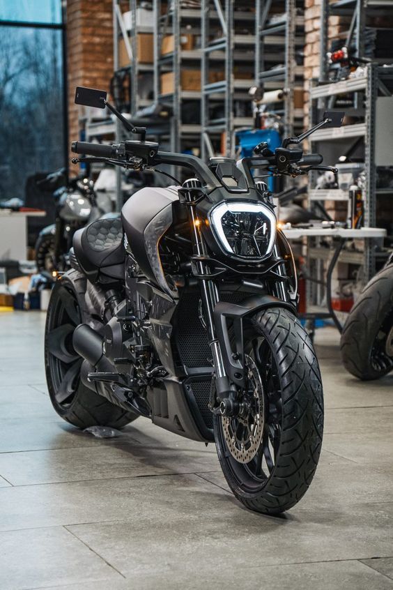 a motorcycle is parked in a garage with other motorcycles behind it and some shelves on the wall