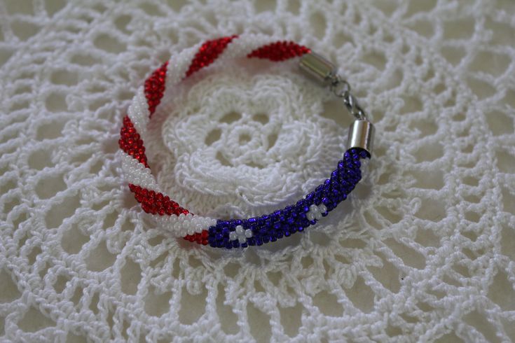 This patriotic seed bead flag bracelet is a great way to show off your patriotism.  It is handmade with size 10 round glass seed beads.  They are strung onto #3 cotton crochet thread and then crocheted together to make the beautiful American flag design.  I do not recommend wearing this product in water since it is made with crochet cotton.  The bracelet can be made into different lengths to accommodate different wrist sizing.  The bracelet is finished off with a lobster claw closure to make it Handmade Patriotic White Beaded Bracelets, Patriotic White Handmade Beaded Bracelets, Handmade Patriotic Beaded Bracelets For 4th Of July, Handmade Patriotic Blue Beaded Bracelets, Handmade Patriotic Blue Beaded Bracelet, Flag Bracelet, American Flag Design, Crochet Thread, Hippie Bracelets