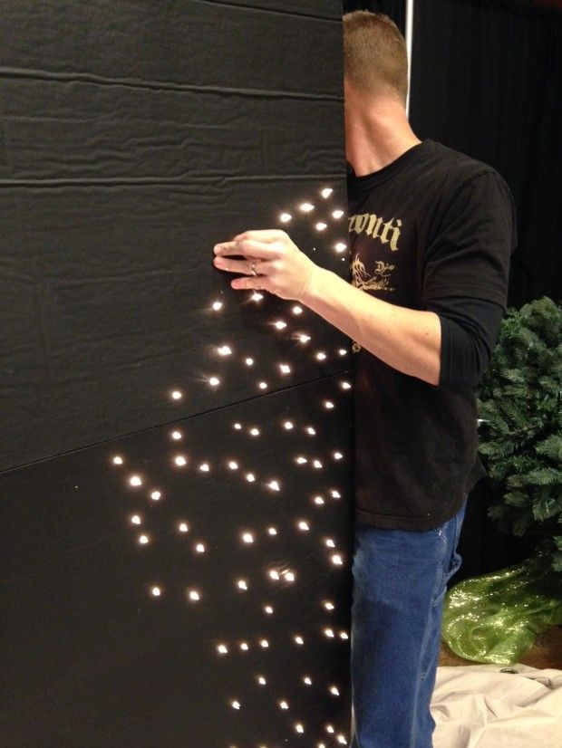 a man standing in front of a black wall with white lights on it's side