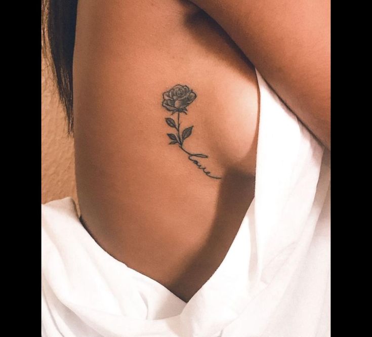 a woman's arm with a rose tattoo on her left side ribcage