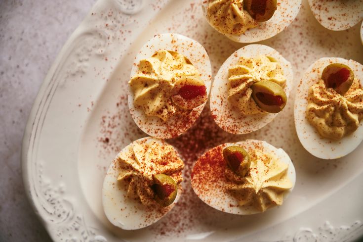 deviled eggs on a white platter with sprinkles and seasoning