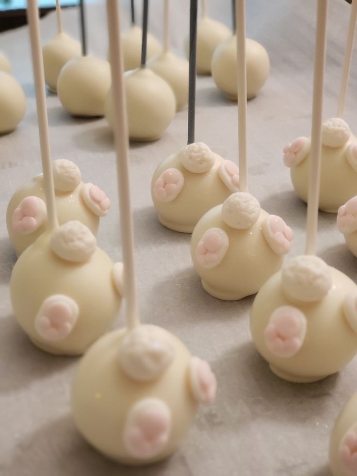 there are many white cake pops with pink and white frosting on them, all lined up in rows