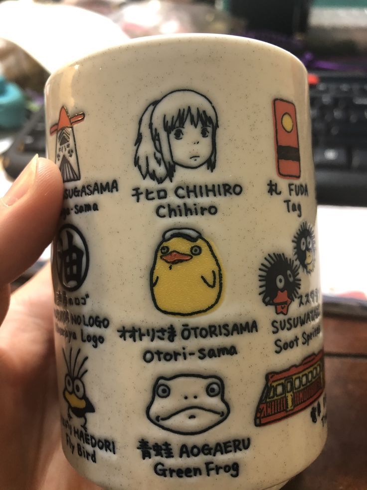 a hand holding a coffee cup with various stickers on it