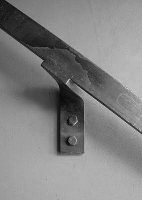 a black and white photo of a knife on a table with the blade still attached to it