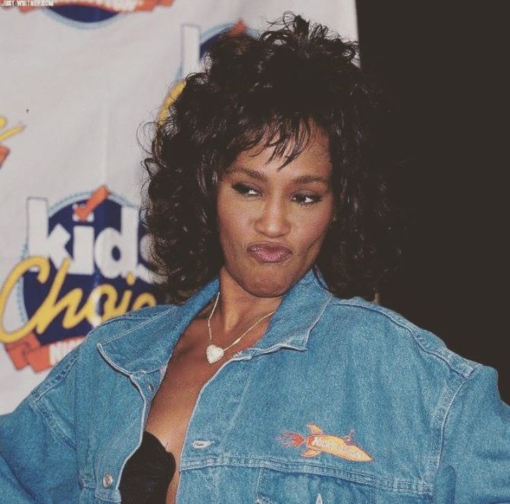 a woman wearing a jean jacket standing in front of a sign