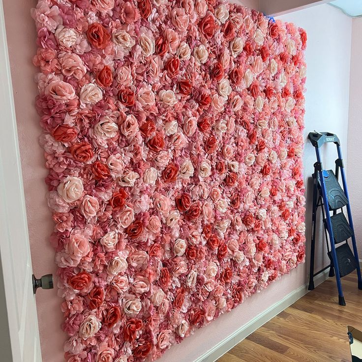 a large pink flowered wall hanging on the side of a room next to a ladder