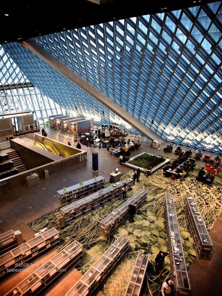 the inside of an airport with people walking around and luggage carts on the ground in front of them