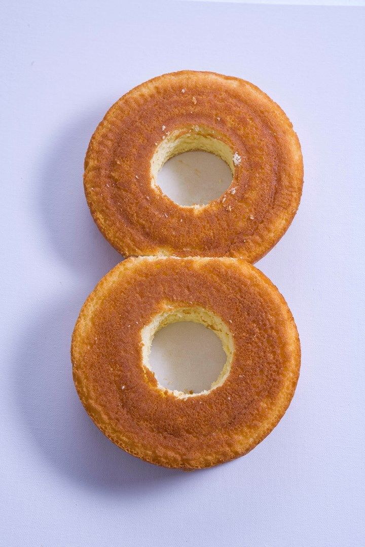 two glazed donuts sitting on top of a white countertop next to each other