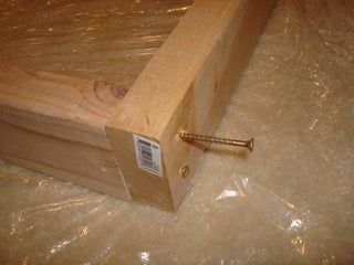 a wooden box with screws in it sitting on the ground next to some plastic