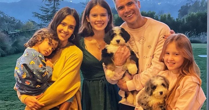 the family is posing for a photo with their two children and one dog in front of mountains