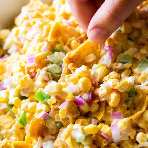 a person is dipping some kind of food into a white bowl filled with corn and onions