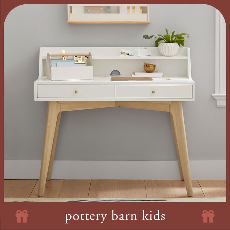 a white desk with two drawers and a plant on it in front of a gray wall