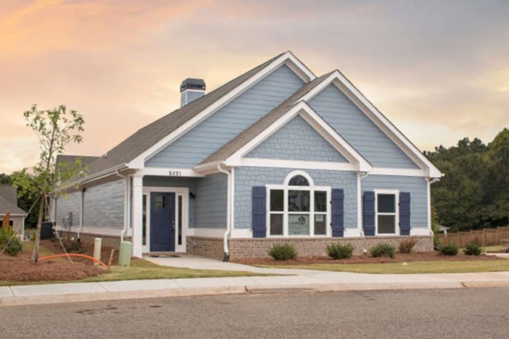 a blue house with white trim and shutters on the front door is shown at sunset