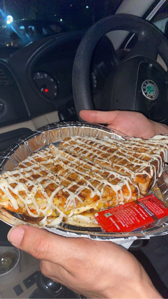 a person is holding a waffle cake in their hand and steering wheel behind him