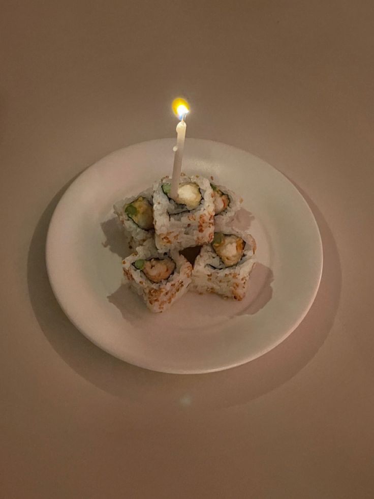 sushi on a plate with a lit candle in the middle, ready to be eaten