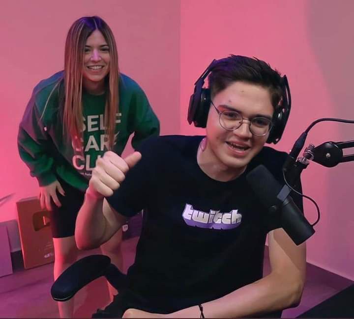 two young people sitting in front of microphones with one giving the thumbs up sign