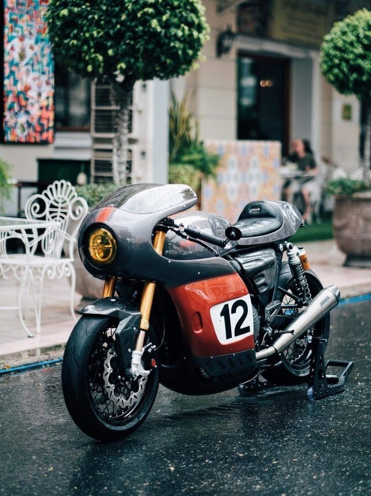 a motorcycle is parked on the street in front of a building with potted plants