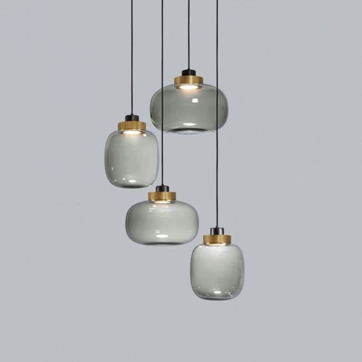 three white and gold glass pendants hanging from a ceiling fixture in a gray room