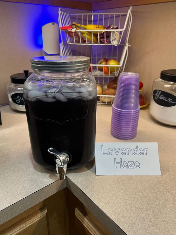 a glass jar filled with liquid sitting on top of a counter next to a sign that says lavender haze