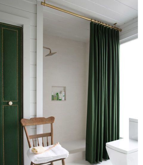 a white toilet sitting next to a green door in a bathroom with a wooden chair