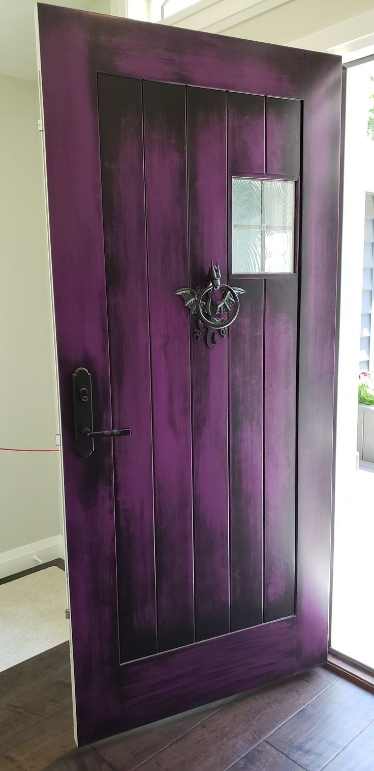 the door is painted purple and has a metal handle on it's front door