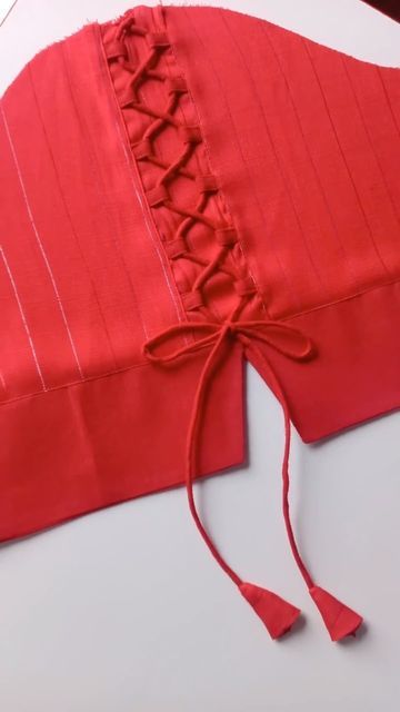 a piece of red fabric with a tie around it's neck and two pieces of white material on the table