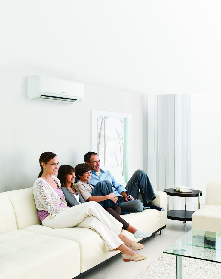 three people sitting on a couch watching something on the tv in a living room with white walls