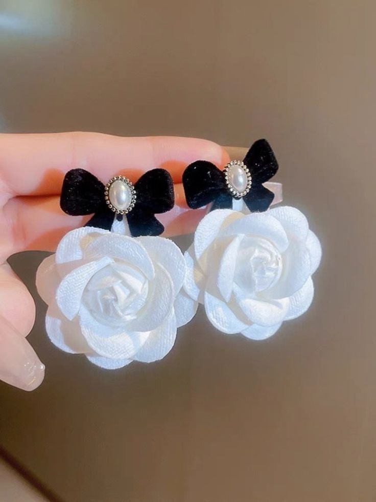 Redefine your style with these stunning flower dangling earrings that feature black velvet ribbon accents and easy push back closure. Every time you wear them, they will evoke joyful feelings and inspire you to embrace your unique beauty. Measurement: 3-5 cm Elegant Adjustable Flower Earrings, Elegant Adjustable Earrings With Flower Decoration, White Flower Earrings For Evening, Elegant Earrings With Flower Decoration And Adjustable Fit, Elegant Black Flower Earrings For Party, Elegant Adjustable Handmade Flower Earrings, Party Flower Earrings, Elegant Black Flower Earrings For Wedding, Black Bow Earrings For Party