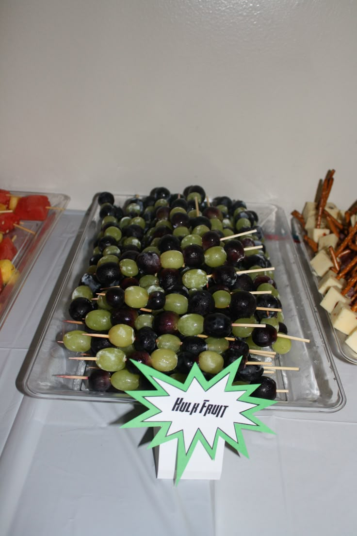 olives and cheese skewers are displayed in trays on a white table