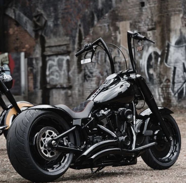 a black and silver motorcycle parked in front of a wall with graffiti painted on it