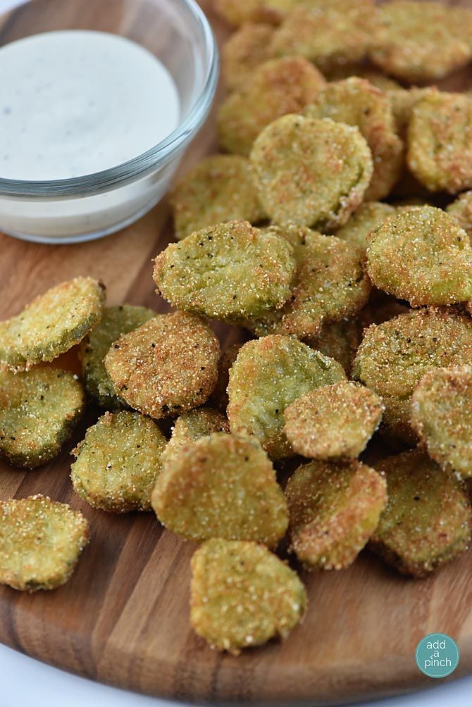 small pieces of fried food on a wooden cutting board next to a bowl of ranch dressing