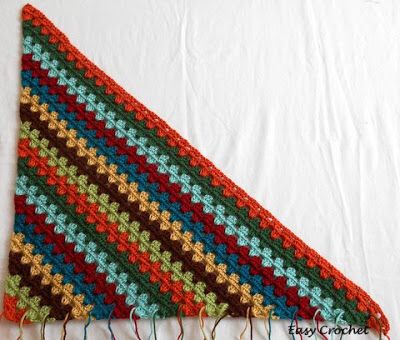 a multicolored crocheted blanket laying on top of a white tablecloth