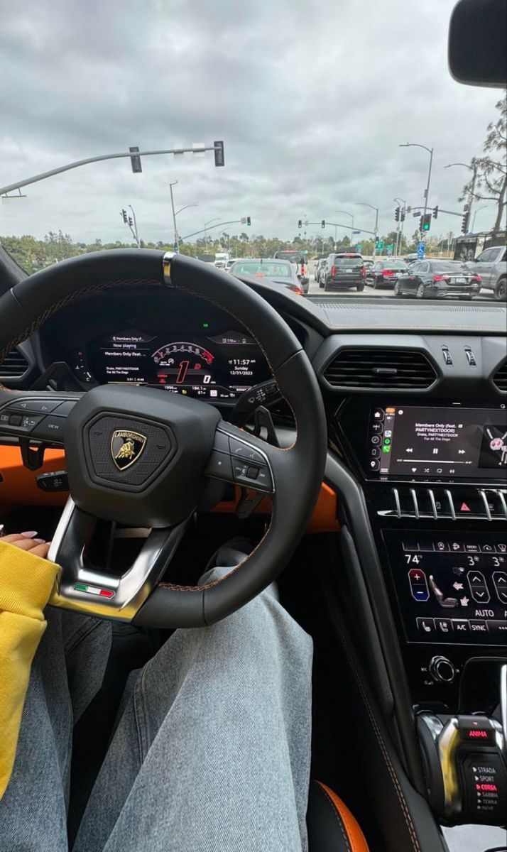 a man sitting in the driver's seat of a car with his hands on the steering wheel