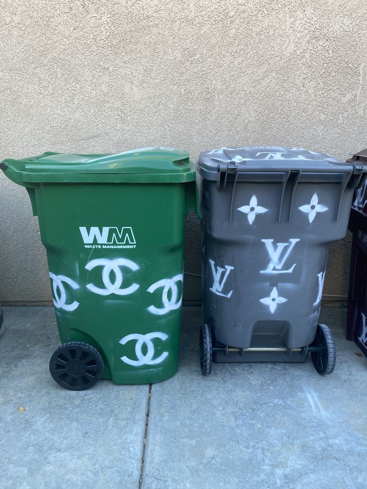 three trash cans sitting next to each other on the sidewalk, one with an eye drawn on it