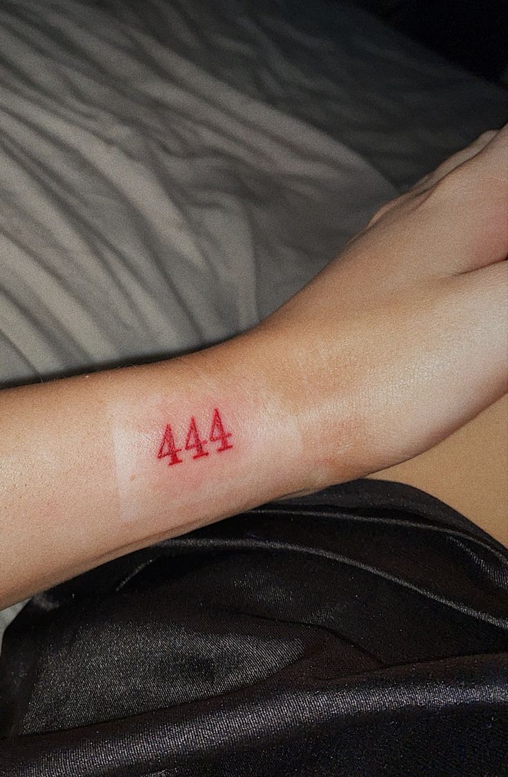 a person with a red tattoo on their arm that says 444 written on it