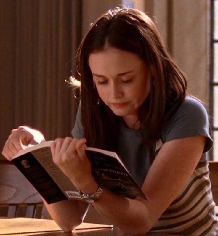 a woman sitting at a table reading a book