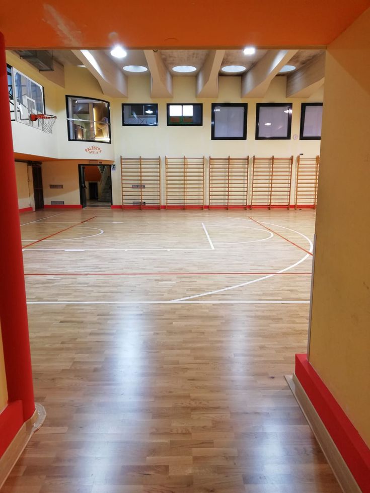 an empty gym with hard wood floors and red pillars