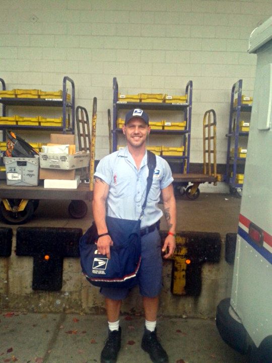 a man standing in front of some shelves holding a bag and smiling at the camera