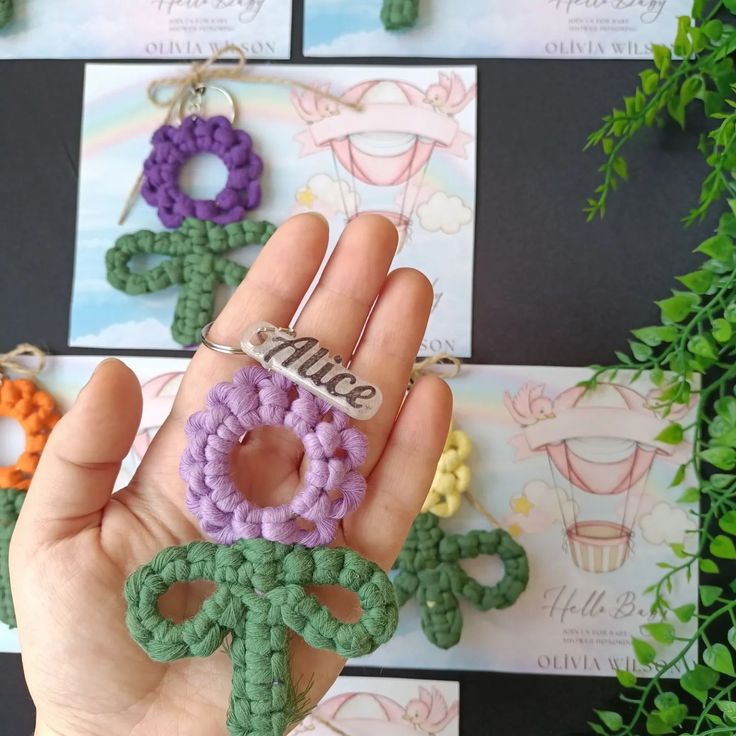 a hand holding a crocheted ring with the word hello written on it in front of several other items