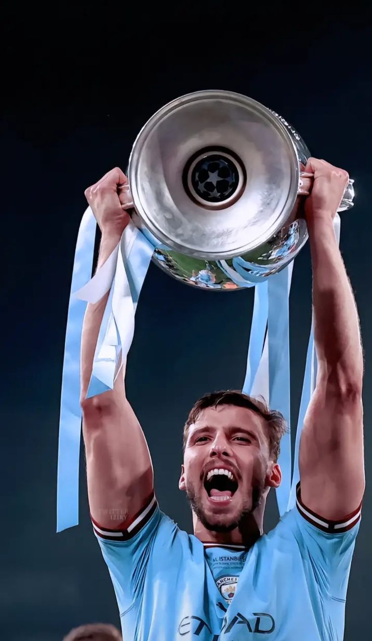 a man holding up a soccer trophy in the air with his hands above his head