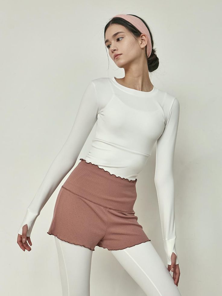 a woman in white top and pink skirt posing for the camera with her hands on her hips